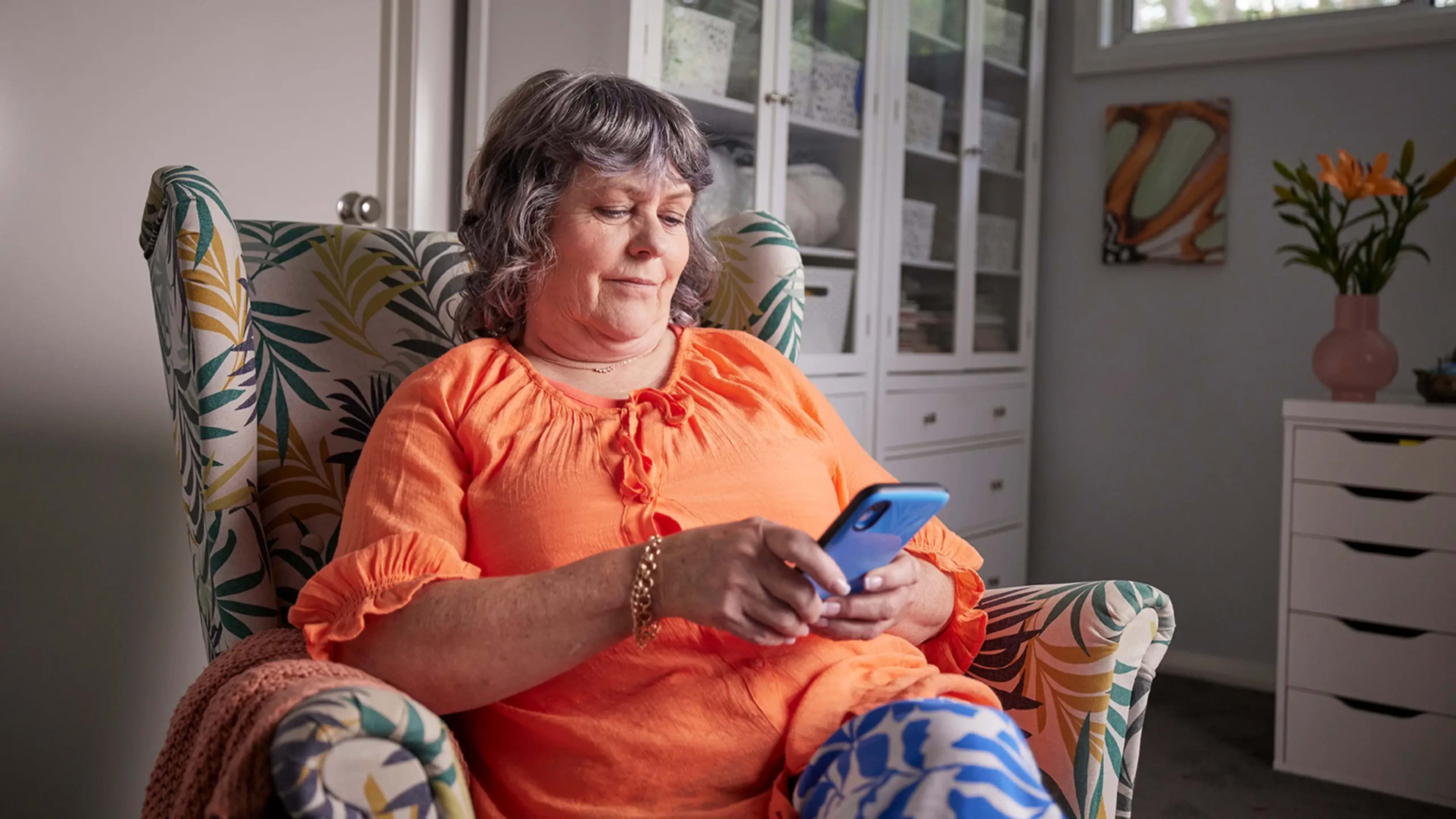Support worker sitting in armchair while looking at their phone.