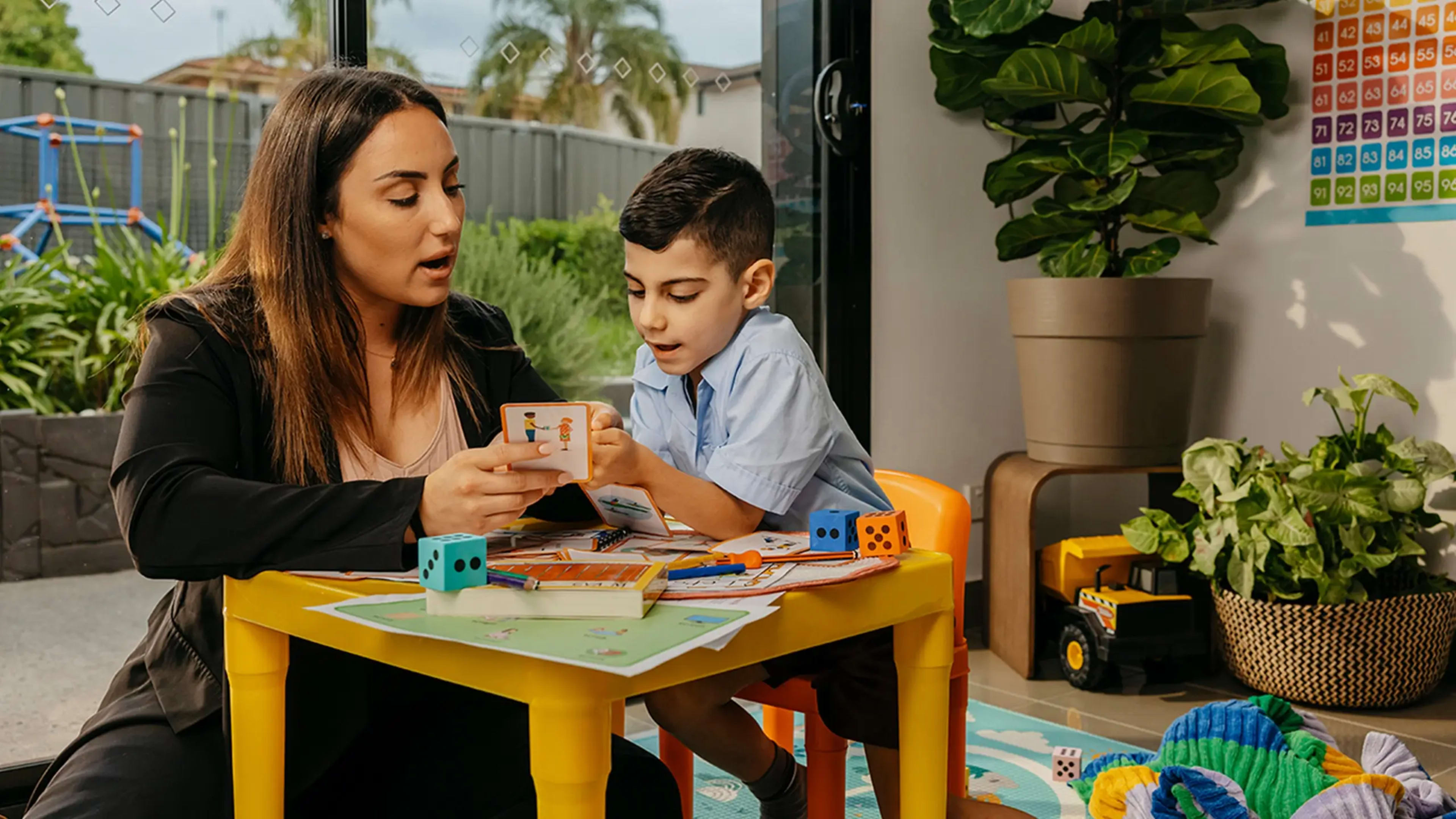 Speech pathologist and child with speech disorder sound out words together from a flash card.