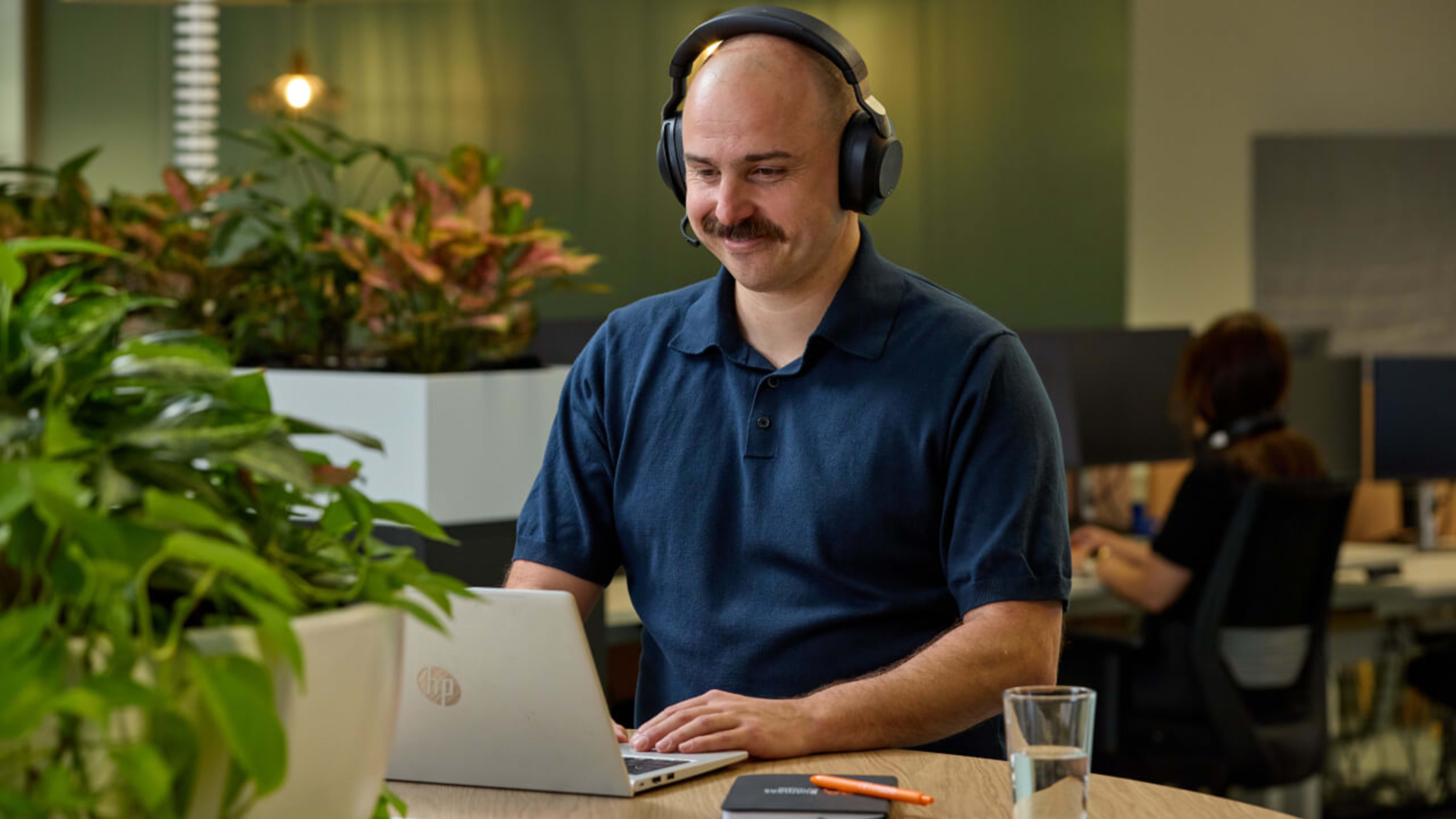 An account manager wears headphones in front of a laptop in an office.