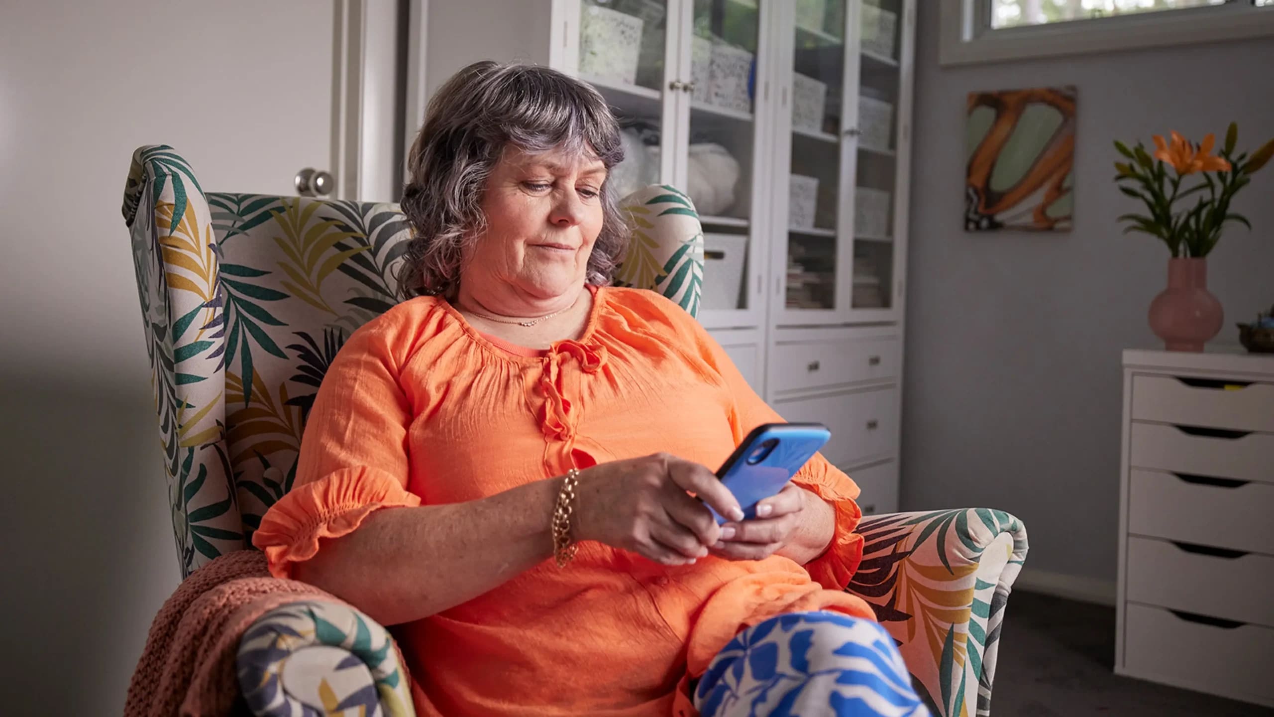 Support worker sitting in armchair while looking at their phone.