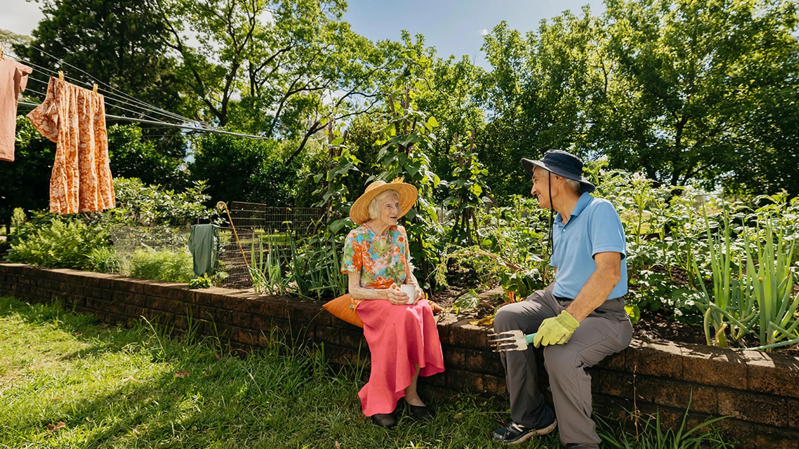 Support worker prunes plants in the garden while chatting to their older client.