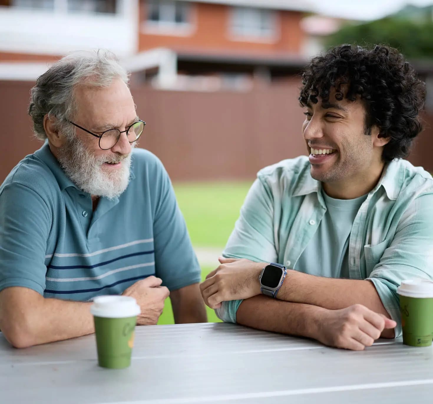 An older man and his support worker drinking coffee together.