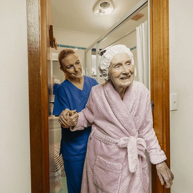 A nurse helps her client out of the bathroom.