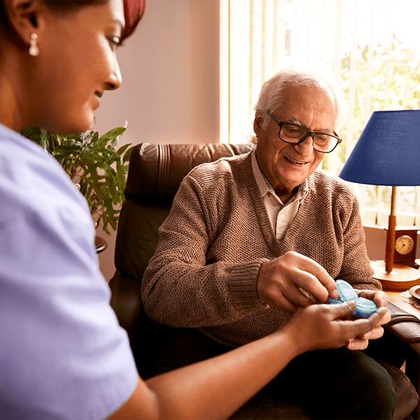 A nurse dispenses medication to her older client.